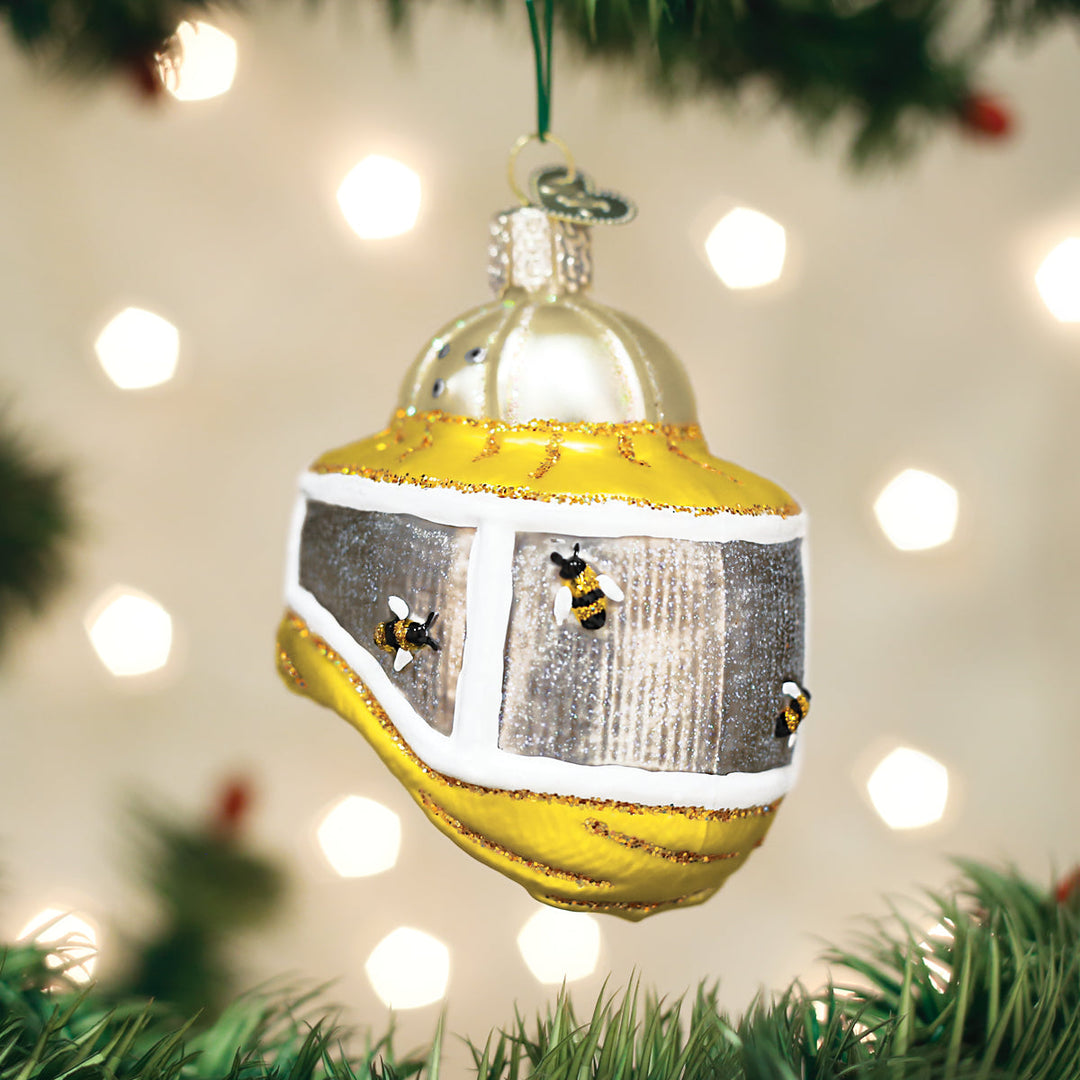 Beekeeper's hood bee Christmas ornament hanging on a tree branch with warm bokeh lights