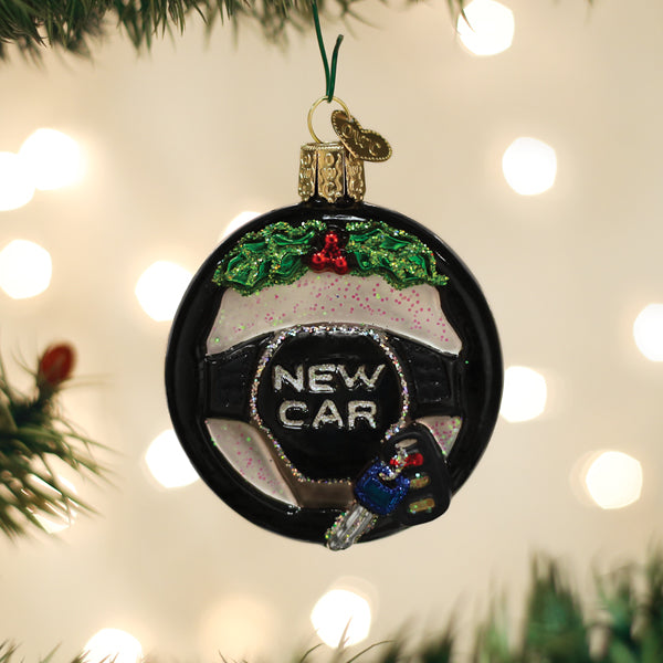 New Car steering wheel ornament hanging on a Christmas tree with warm bokeh lights