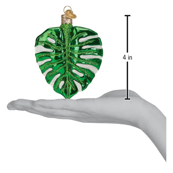 Monstera leaf ornament on an open palm beside a 4 inch height marker