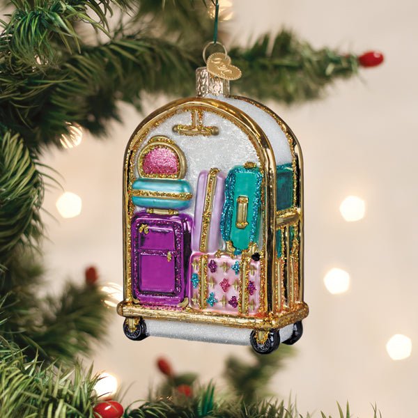 Hotel luggage cart Christmas ornament hanging on a tree branch with warm bokeh lights