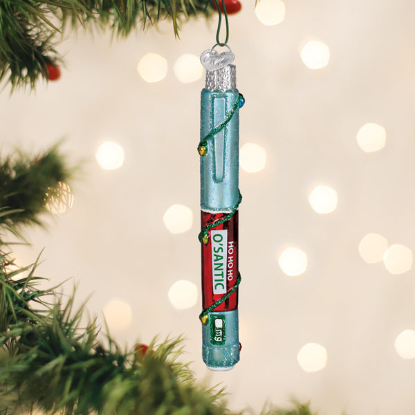 Injection pen funny Christmas ornament hanging on a tree branch with warm bokeh lights