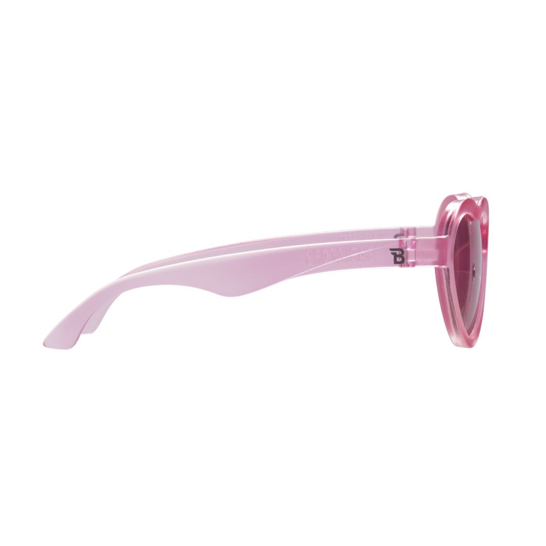 Side profile of fuchsia heart-shaped kids sunglasses showing the light pink flexible temple arm.