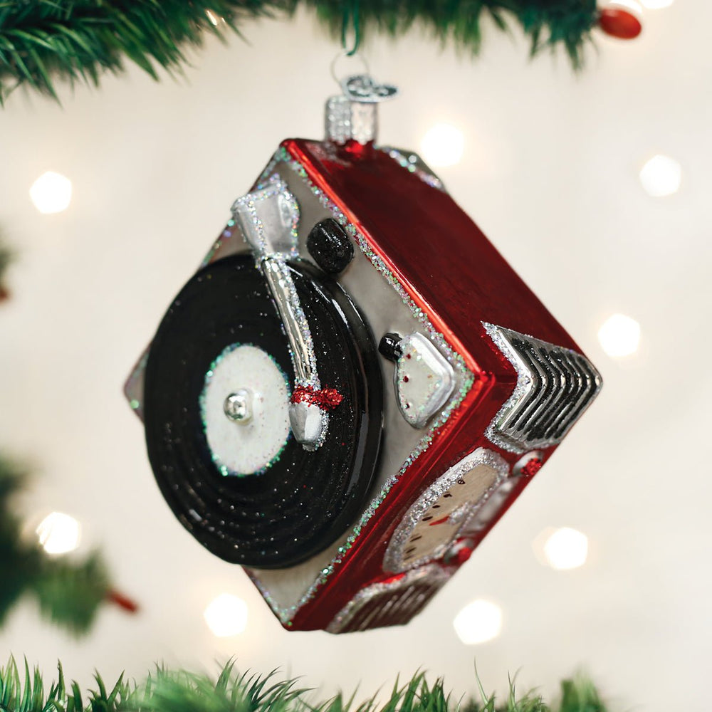 Red record player ornament hanging on the diagonal on a lit Christmas tree