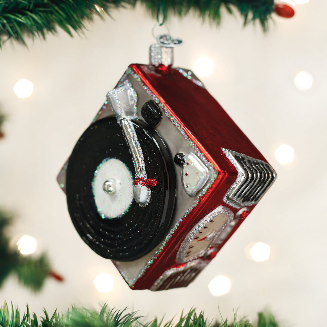 Red record player ornament hanging on the diagonal on a lit Christmas tree