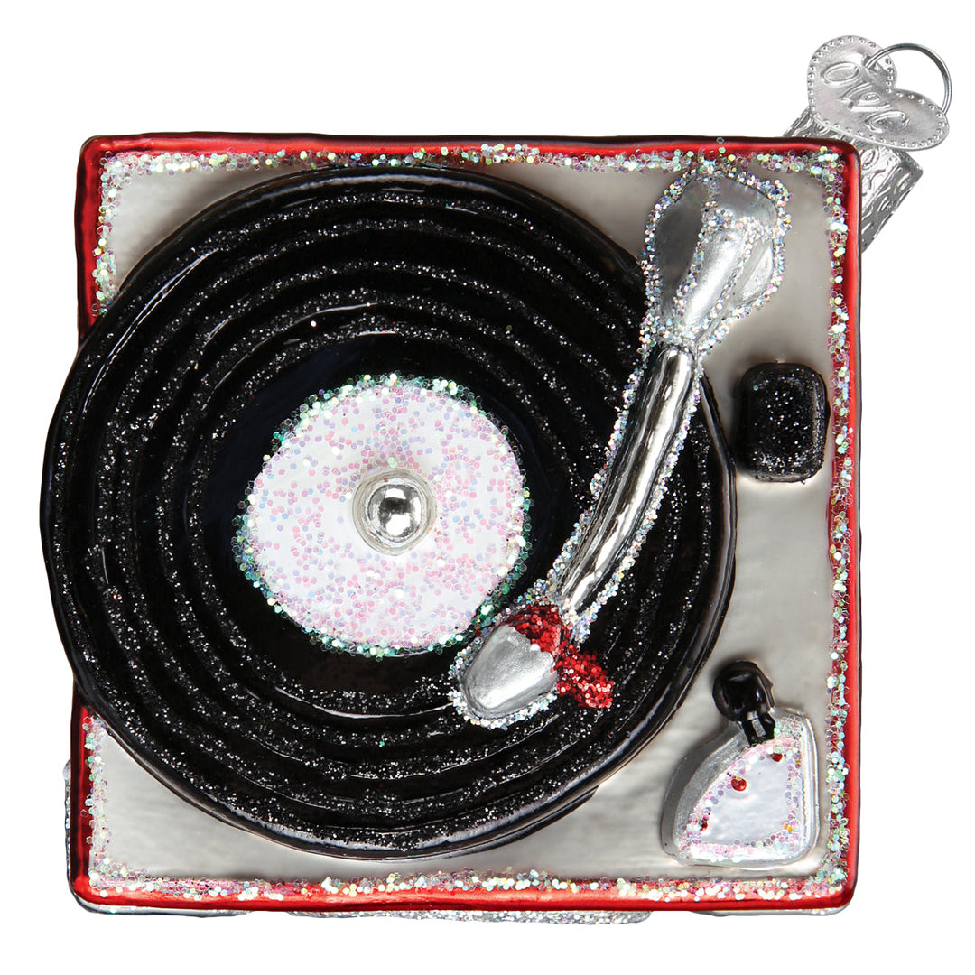 Top-down view of the record player glass ornament with black glitter record and silver tone arm, on white