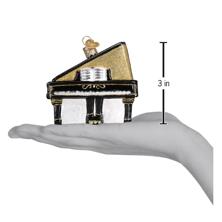 Baby grand piano ornament on an open palm beside a 3 inch height marker