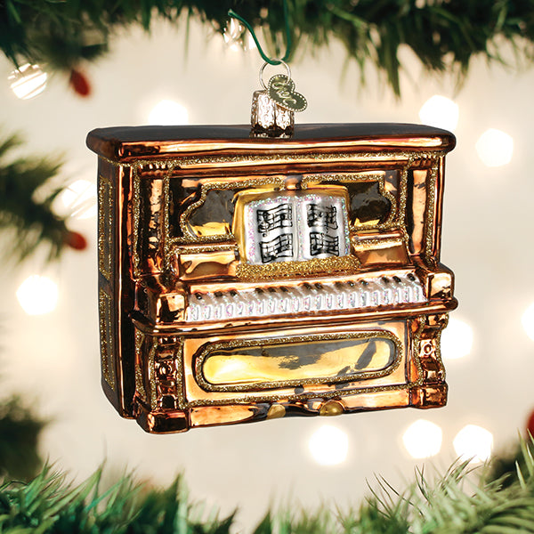 Upright piano Christmas ornament hanging on a tree branch with warm bokeh lights