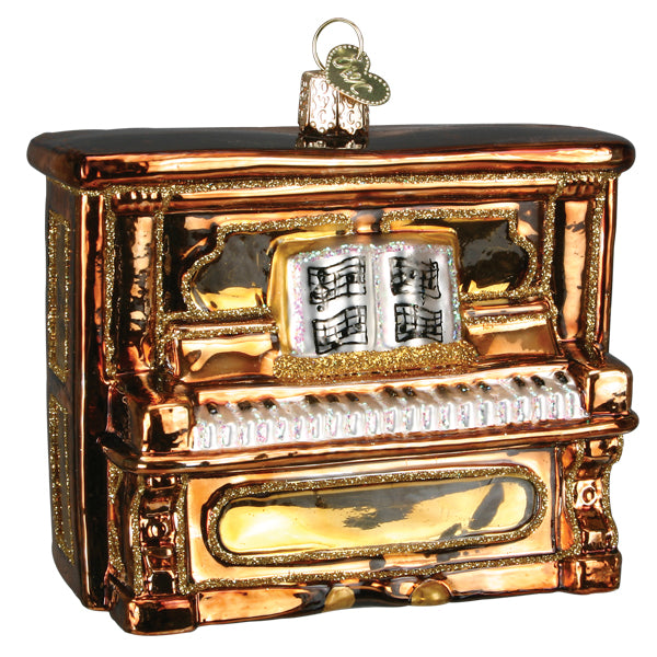 Polished brown upright piano ornament with gold trim, white keys, and open sheet music on a white background
