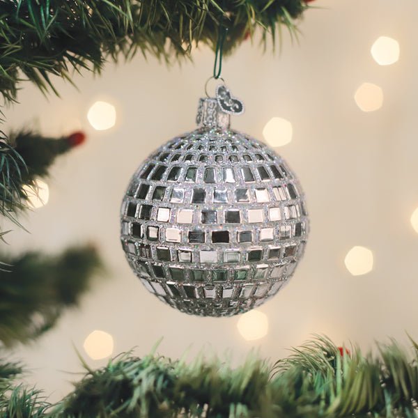 Silver disco ball ornament hanging on a lit Christmas tree with warm bokeh lights