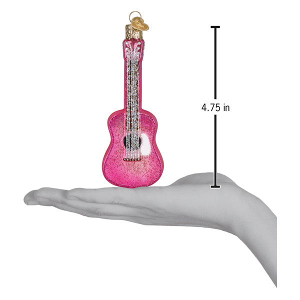Pink glitter guitar ornament held above an open palm with a 4.75 inch height marker for scale