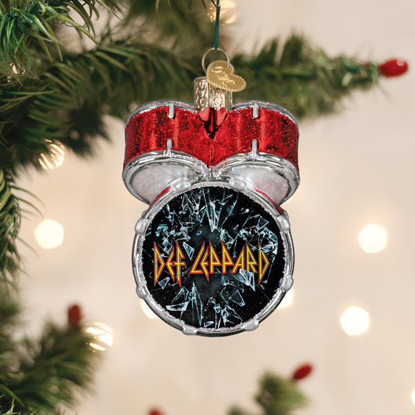 Def Leppard bass drum glass ornament hanging on a lit Christmas tree among green branches