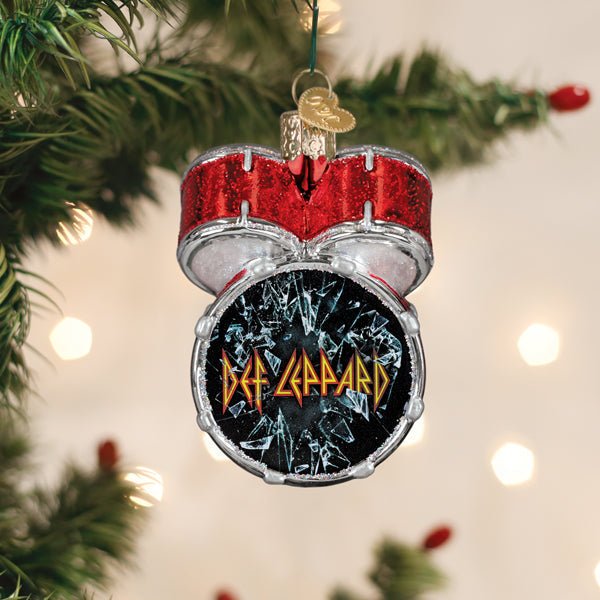 Def Leppard bass drum glass ornament hanging on a lit Christmas tree among green branches