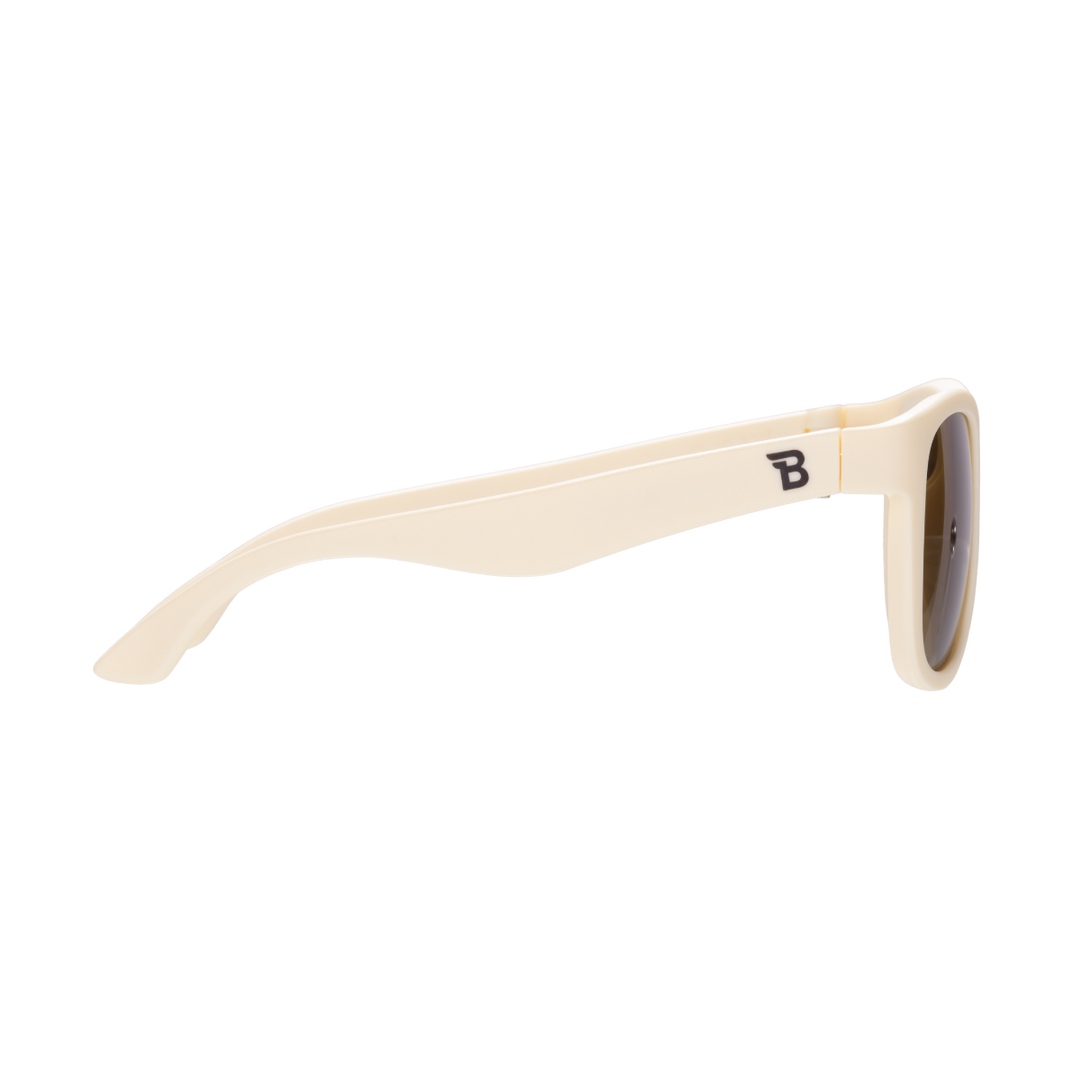 Side profile of cream aviator kids sunglasses showing the flexible temple arm and Babiators logo.