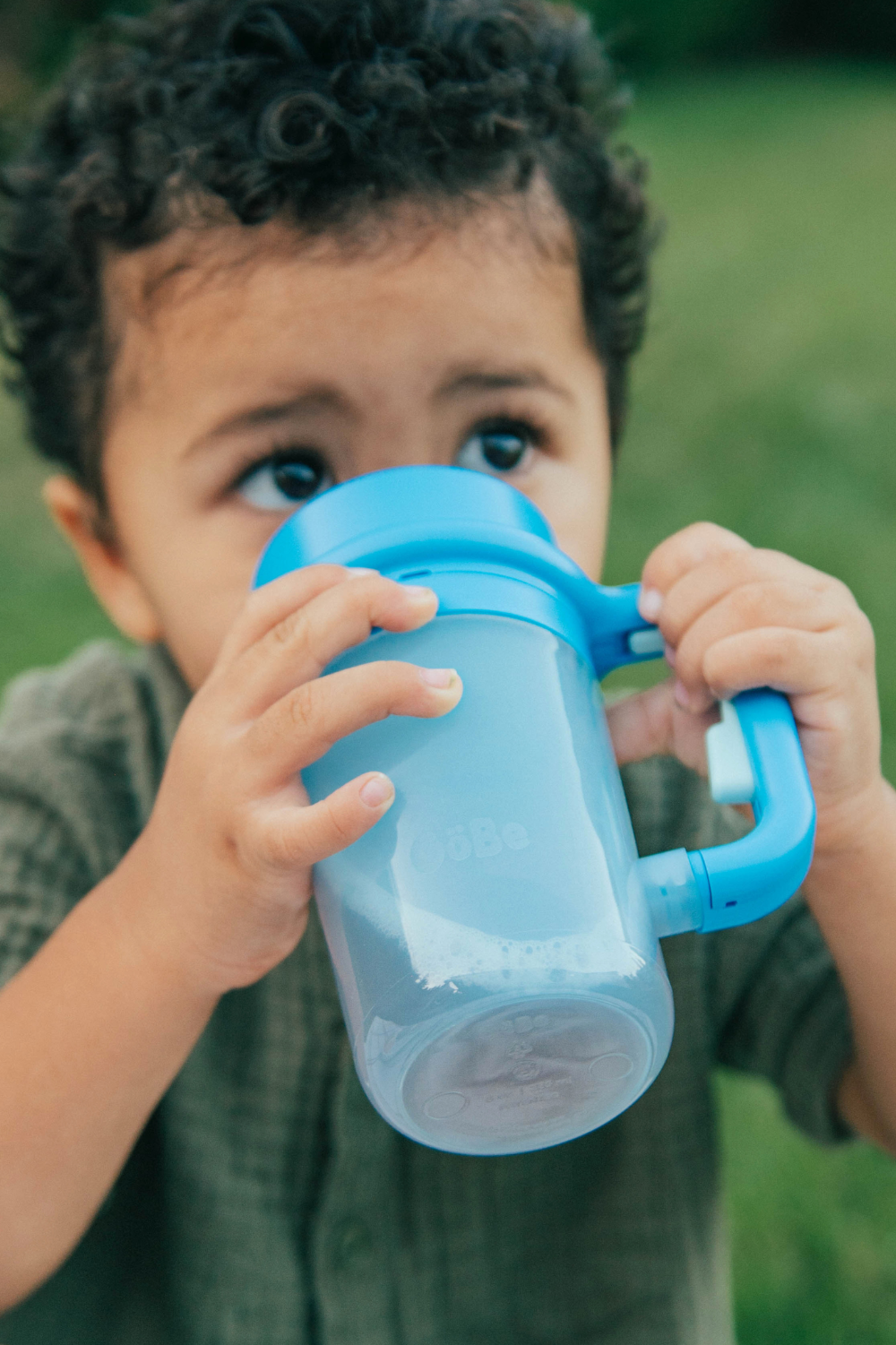 Toddler drinking from the blue Wonder Cup with both hands on the handle