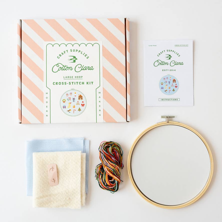 Christmas cross stitch kit contents with blue aida, 8 inch hoop, and rainbow thread