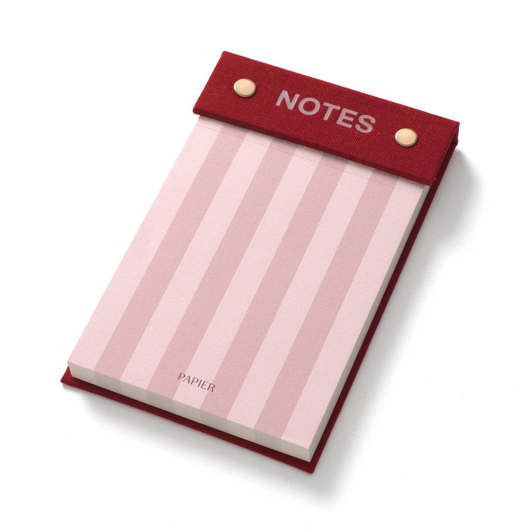 Angled view of the Bloom fabric hardcover notepad showing pink striped tear off sheets, a stocking stuffer for list makers