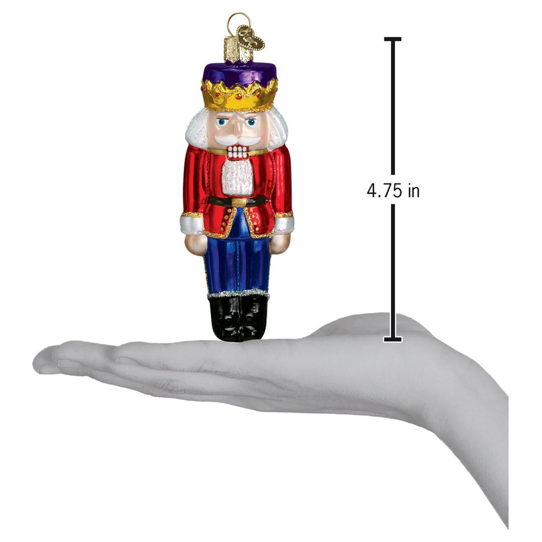 Nutcracker Prince ornament on an open palm beside a 4.75 inch height marker