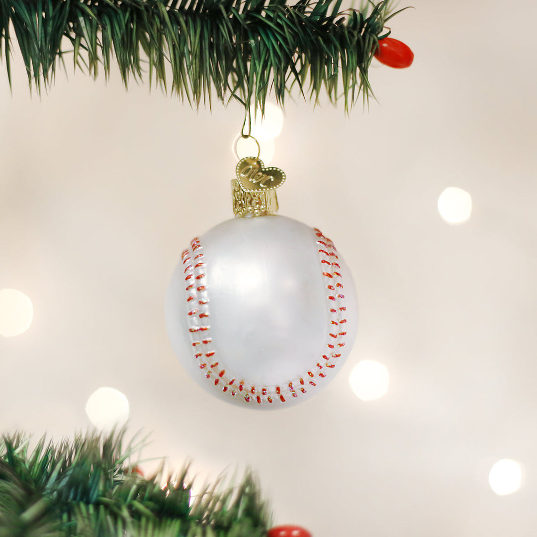 Baseball Christmas ornament hanging from a pine branch against glowing holiday lights
