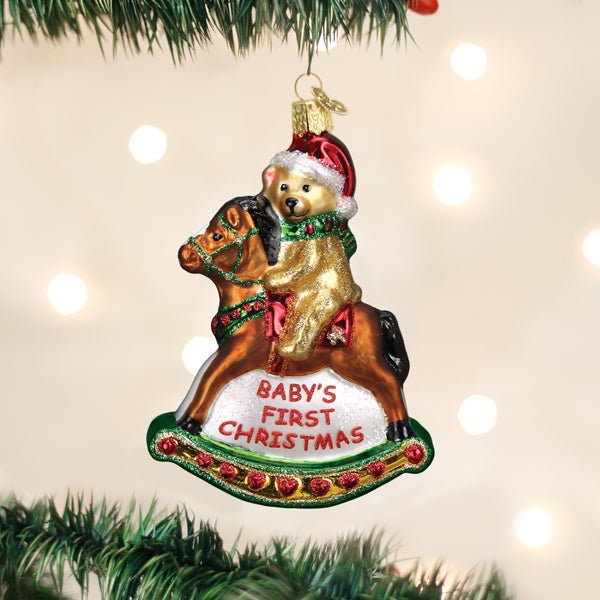 Baby's First Christmas rocking horse teddy ornament hanging on a lit Christmas tree