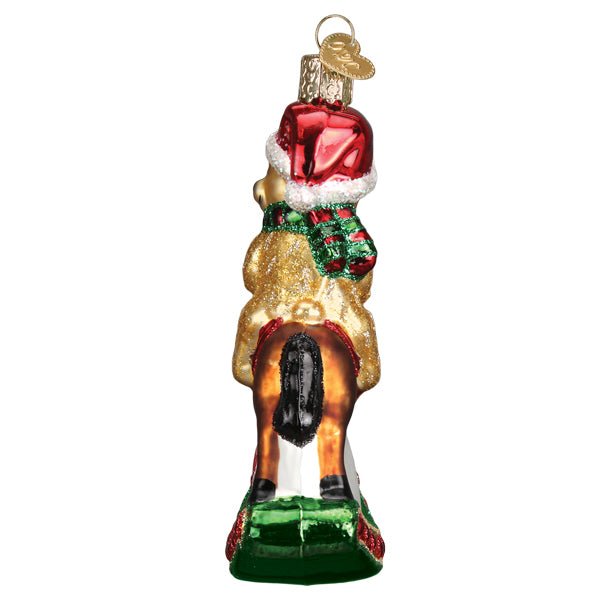 Tail-end view of the rocking horse ornament showing the teddy's red hat and green scarf, on white