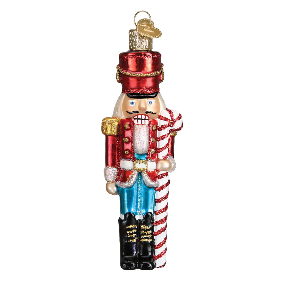 Front of the peppermint nutcracker ornament holding a red and white candy cane, on white