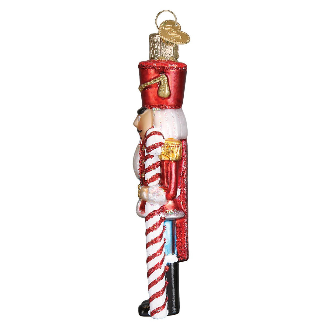 Side of the peppermint nutcracker ornament with the striped candy cane along his arm