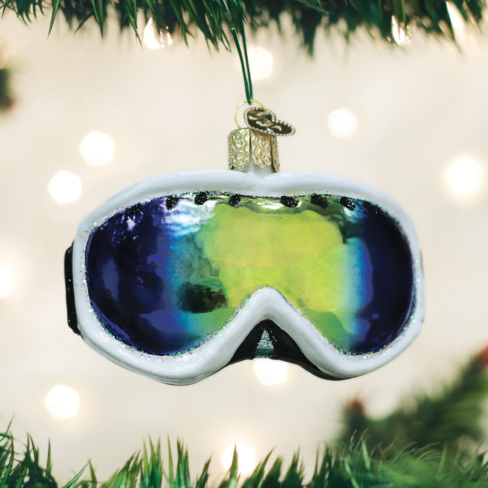Ski goggles Christmas ornament hanging on a pine tree with twinkle lights glowing behind