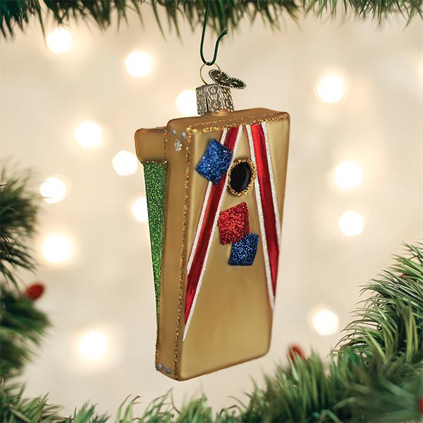 Cornhole board ornament hanging on a Christmas tree with glowing lights, a gift for backyard game fans