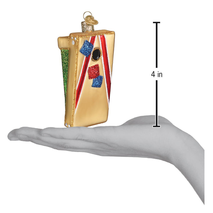 Cornhole board ornament above an open hand with a 4 inch scale marker beside it