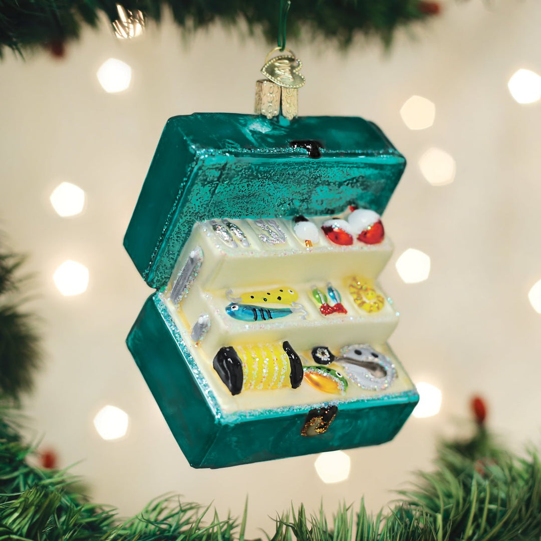Open teal tackle box ornament hanging on a lit Christmas tree with warm bokeh lights