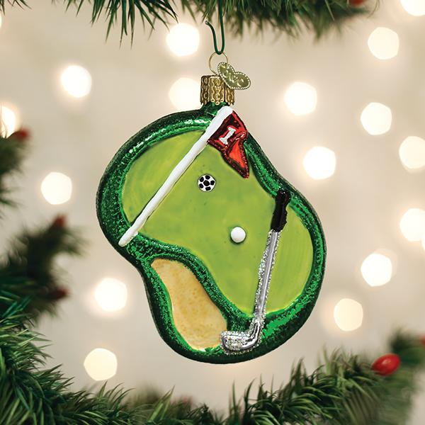Golf putting green ornament hanging on a lit Christmas tree with soft bokeh lights