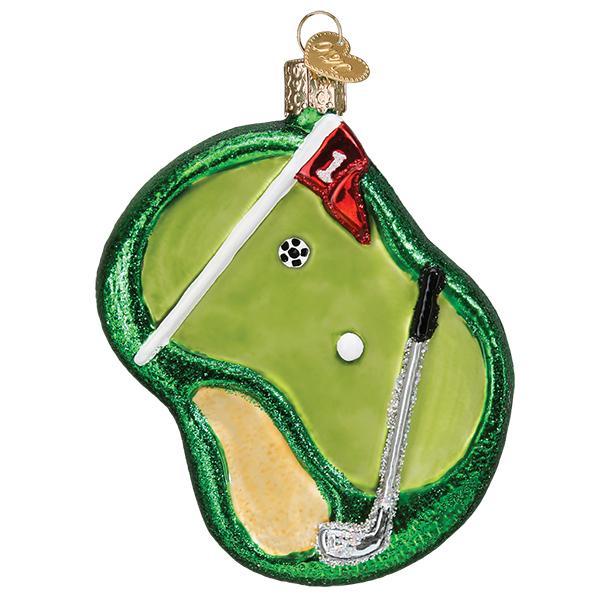 Front of the golf putting green glass ornament with red pin flag, putter, white ball, and sand trap, on white