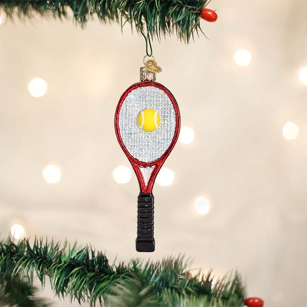 Tennis racket Christmas ornament hanging from a pine branch with warm twinkle lights