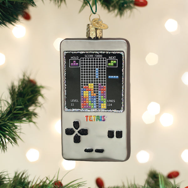 Tetris handheld game ornament hanging on a lit Christmas tree among green branches