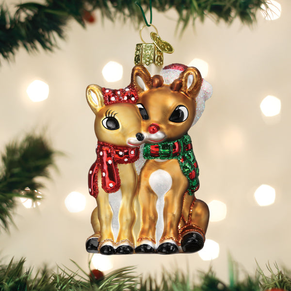 Rudolph and Clarice ornament hanging on a Christmas tree with soft holiday lights behind