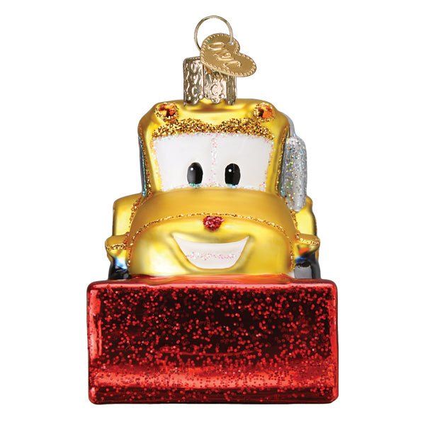Head-on view of the bulldozer ornament showing its smiling face above the red glitter blade, on white
