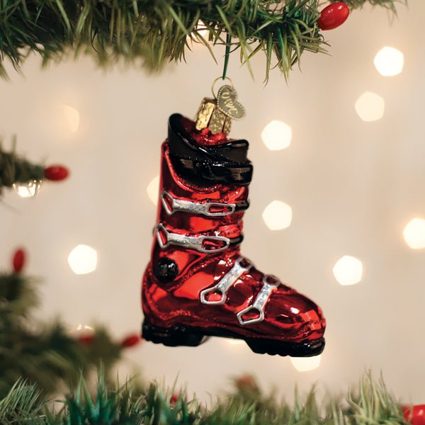 Red ski boot ornament hanging on a lit Christmas tree with warm bokeh lights