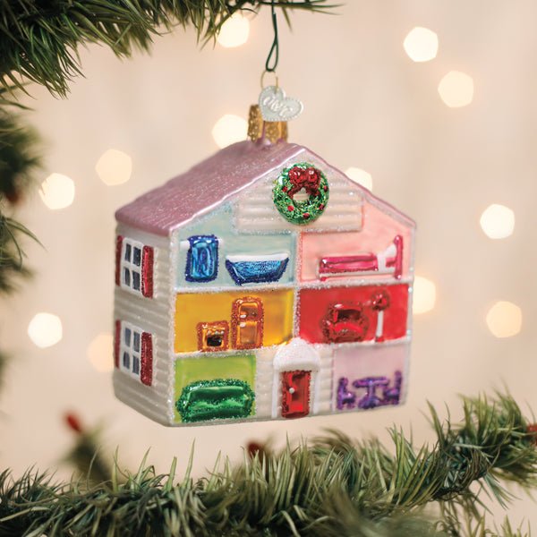 Colorful glass dollhouse ornament hanging on a lit Christmas tree with warm bokeh lights