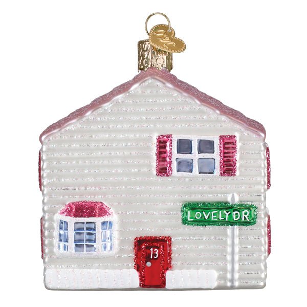 Street side of the dollhouse ornament with white siding, a red door, and a Lovely Dr sign, on white