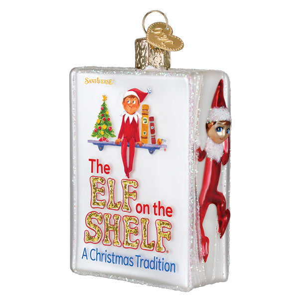 The Elf on the Shelf book glass ornament, front three-quarter view of the cover with the elf on the spine, on white