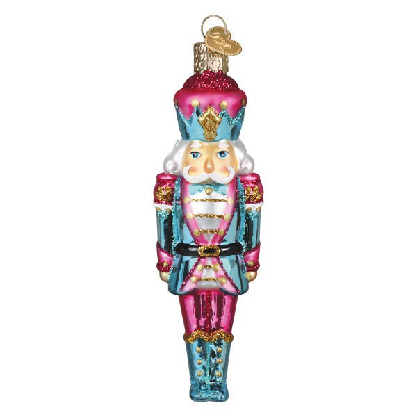 Front of the pastel nutcracker ornament in a pink hat, aqua coat, and pink trousers, on white