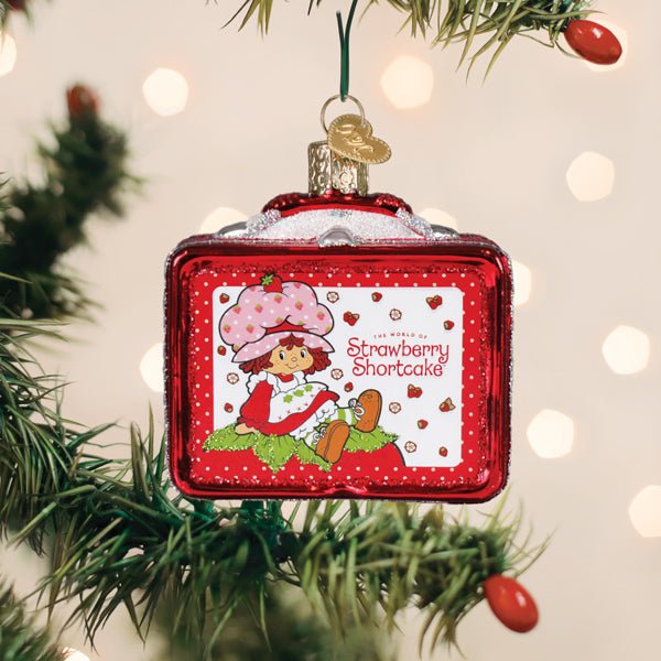 Strawberry Shortcake lunchbox ornament hanging on a Christmas tree with red berry picks nearby