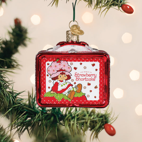 Strawberry Shortcake lunchbox ornament hanging on a Christmas tree with red berry picks nearby