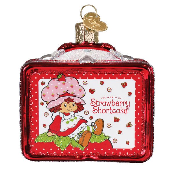 Red glass lunchbox ornament with Strawberry Shortcake artwork and a polka dot border, front view on white