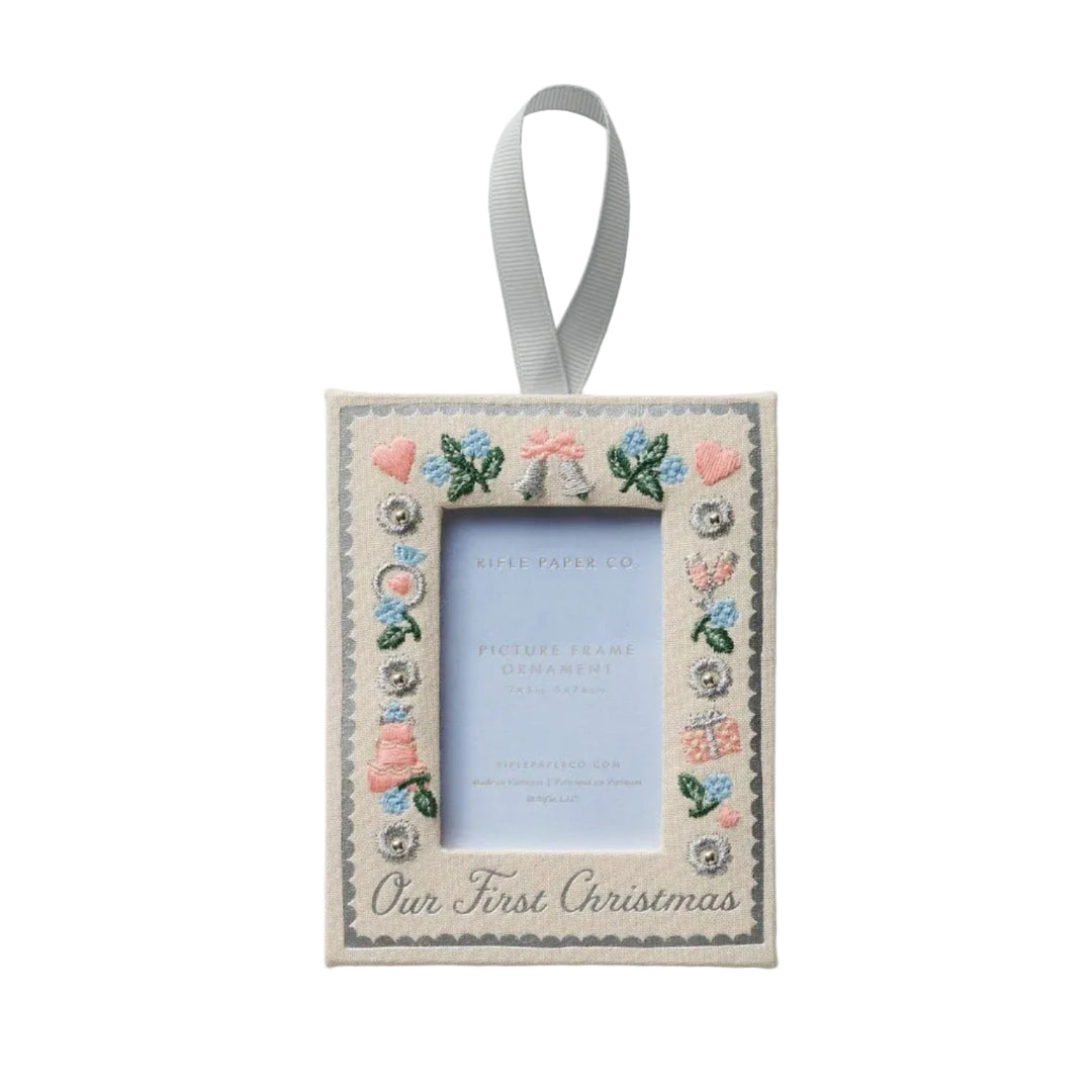 Our First Christmas embroidered frame ornament in cream with silver script, pastel wedding motifs, and silver ribbon