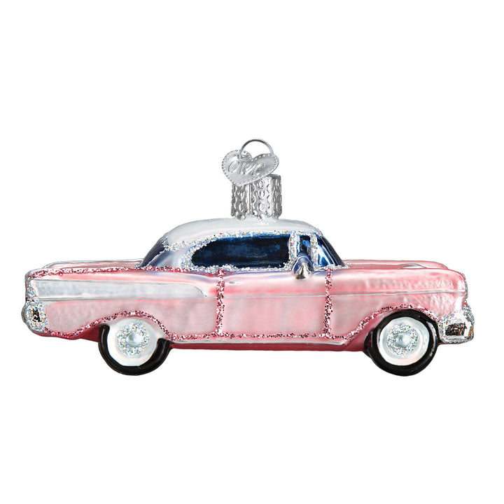 Pink classic car glass ornament with white roof, tail fins, and chrome trim, side view on white