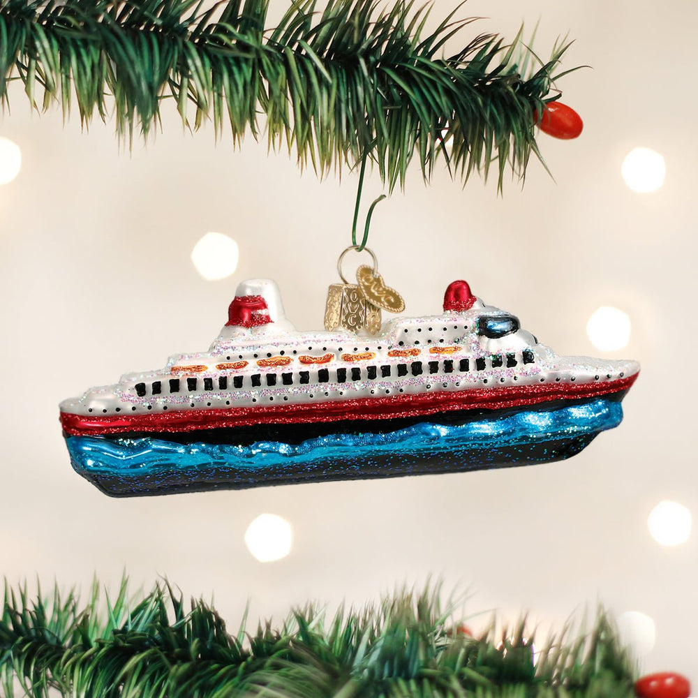 Cruise ship ornament hanging on a lit Christmas tree with warm bokeh lights and red berries