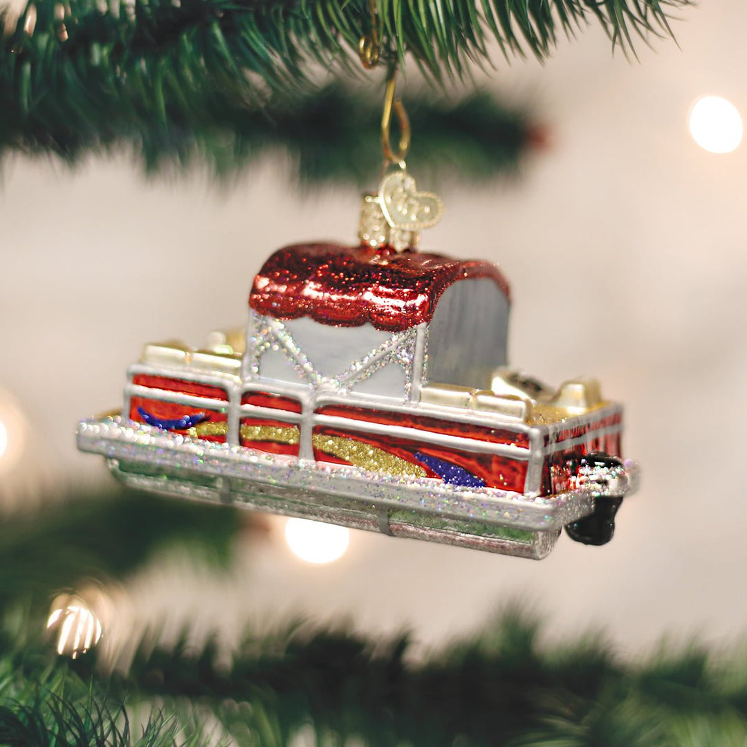 Pontoon boat ornament hanging on a lit Christmas tree with warm bokeh lights
