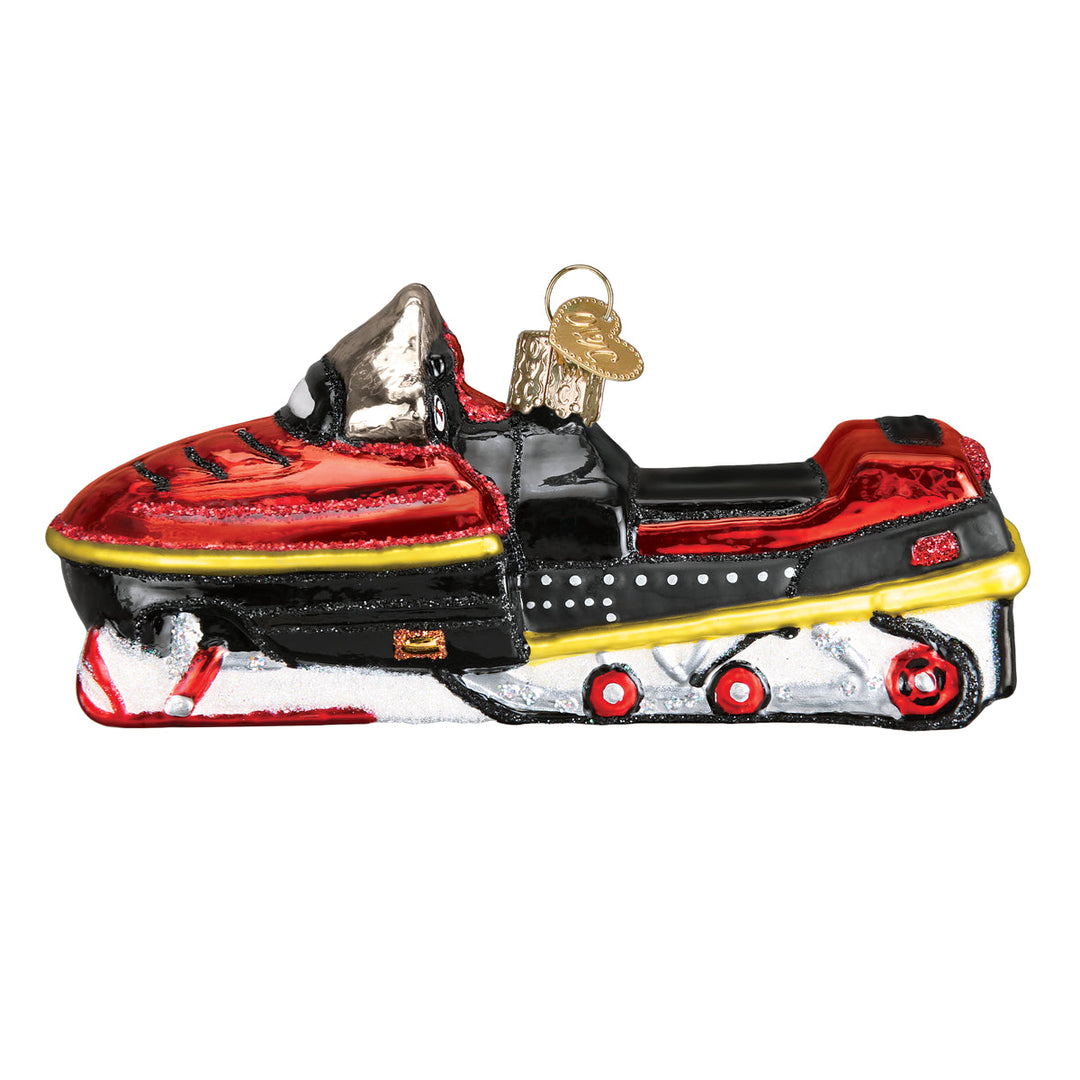 Side view of the red snowmobile ornament with a yellow stripe, black seat, and white skis, on white