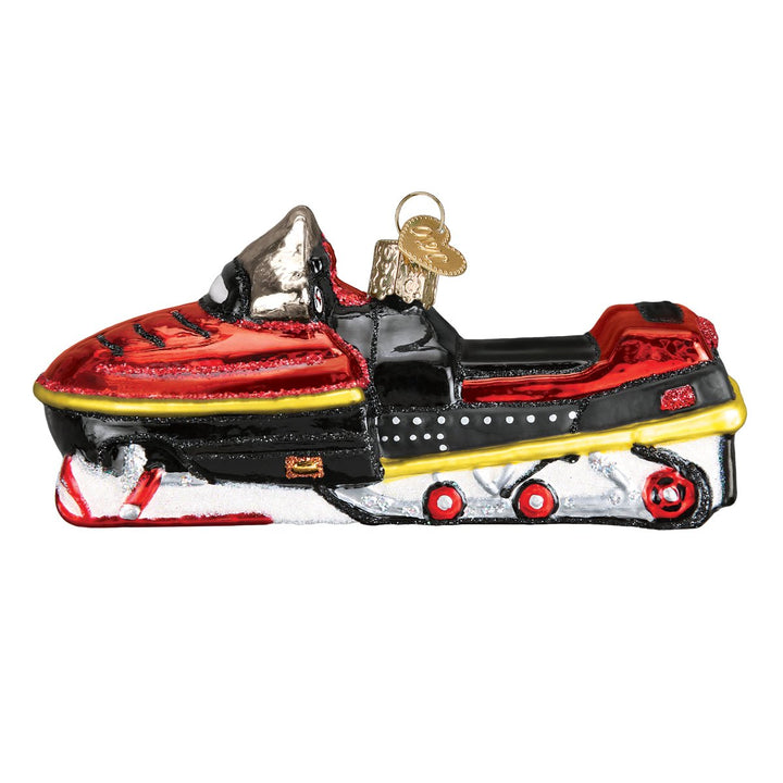 Side view of the red snowmobile ornament with a yellow stripe, black seat, and white skis, on white